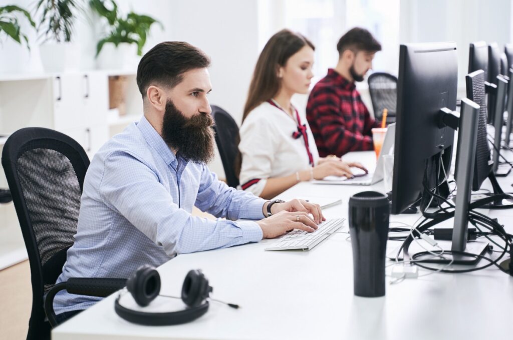 Bearded office worker sat typing on computer