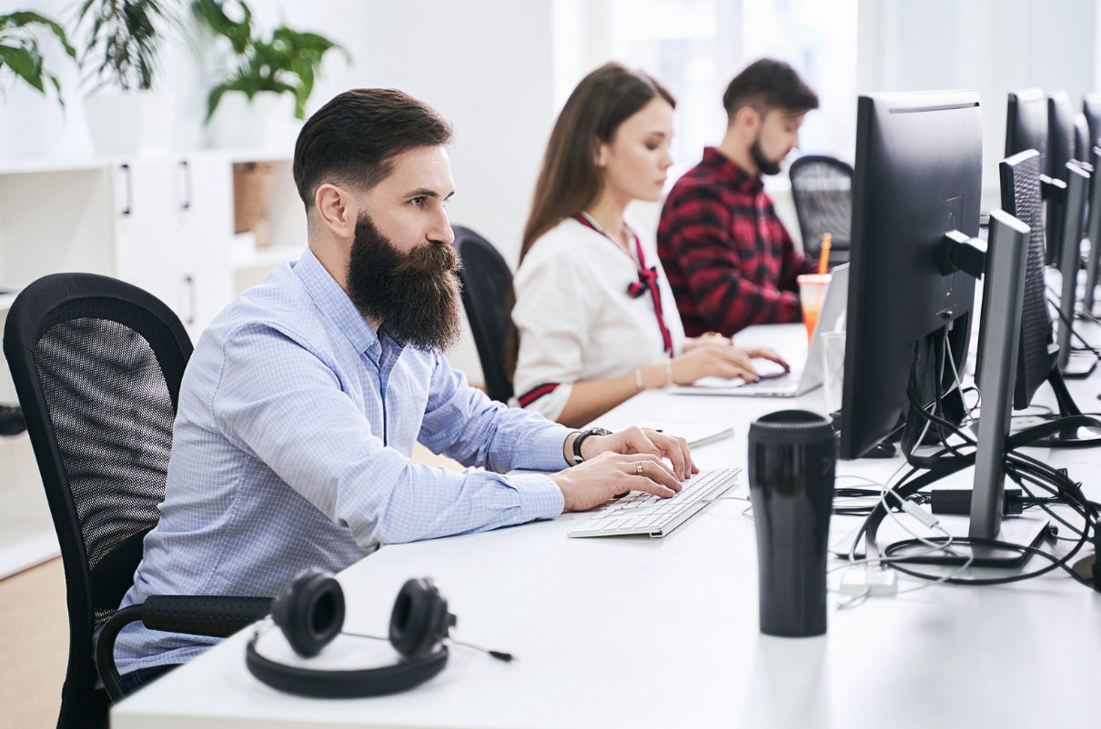 Bearded office worker sat typing on computer