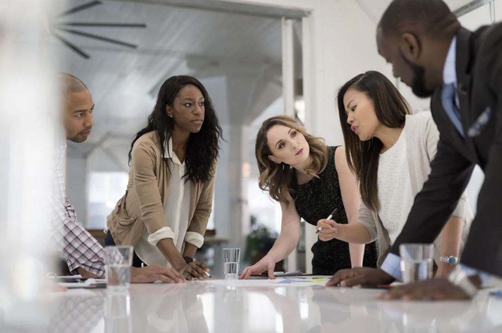 Group of office workers huddled around team lead finalising strategy