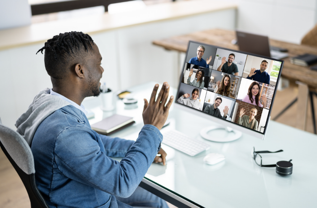 man in video conference waving his hand at others