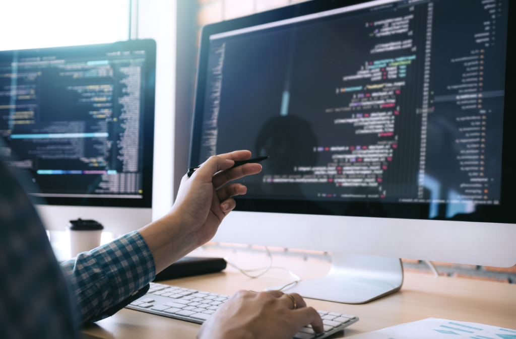pen-holding office worker studying coding on a computer screen