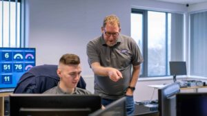 Two Your IT Department cyber security consultants looking at a screen together, with monitoring dashboards on the wall behind them