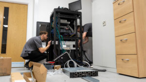 Two Your IT Department engineers installing network cabling and equipment in a server rack